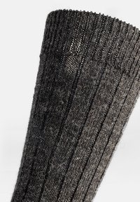 Calentadores de pierna de punto en gris oscuro, con textura acanalada, tejido suave con fibras visibles y un diseño en forma de cono en la parte superior.