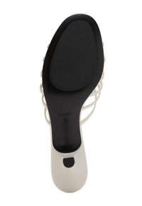Sandale à talons hauts avec une tige lisse de couleur crème, un design de brides transparentes et une semelle en caoutchouc noir texturé pour l'adhérence. Taille 37.