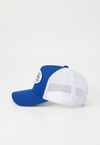 Kék baseball sapka, egyszínű elülső résszel és fehér hálós hátrésszel, a elülső panelen egy logót ábrázoló kerek folttal. Ívelt napellenző.