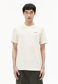 Crème katoenen t-shirt met een ronde halslijn en korte mouwen, voorzien van een contrasterend zwart "ARMEDANGELS" logo op de linkerkant van de borst.