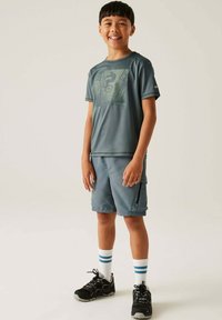 Conjunto atlético gris que incluye una camiseta de manga corta con un estampado gráfico y pantalones cortos a juego. Acompañado de calcetines blancos y azules a rayas, y zapatillas negras.