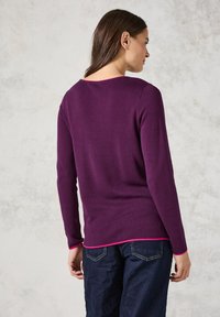Lila longsleeve Pullover mit rundem Ausschnitt, der am Saum eine pinke Akzentfarbe aufweist. Weiche Textur, schlichtes Design und lockere Passform.