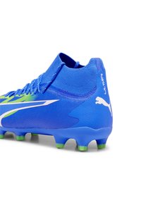 Scarpini da calcio blu con una tomaia testurizzata, dettagli a contrasto gialli e bianchi, design di supporto alla caviglia e suola chiodata verde.