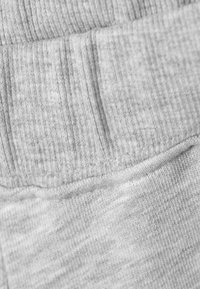 Γκρι ύφασμα με ραβδωτή υφή και λεία επιφάνεια, με ορατές ραφές και ελαστική ζώνη μέσης.