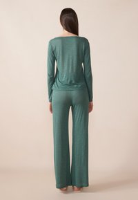 Long-sleeve top and wide-leg pants set in a textured teal fabric, featuring a loose fit and relaxed neckline. Smooth, flowing material.