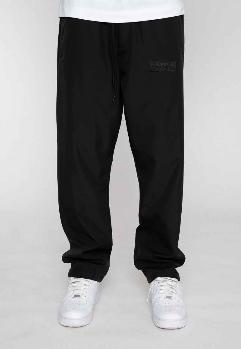 Black jogger pants made from lightweight fabric, featuring an elastic waistband with drawstring, side pockets, and a subtle logo patch.