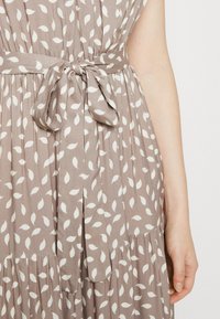 Braunes Kleid mit leichtem Blattmuster, tailliert mit einem Gürtel, mit fließendem Design, Falten und weicher Textur.