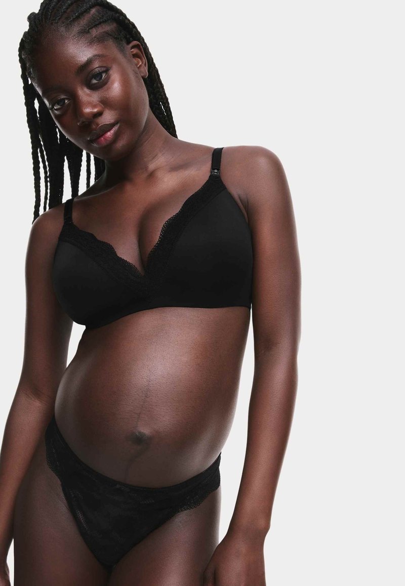 Soutien-gorge noir orné de dentelle avec un décolleté plongeant, assorti à une culotte noire en dentelle. Texture lisse, coupe ajustée et éclat subtil.