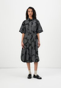 Gray dress with a floral pattern, short sleeves, front buttons, and a belted waist. Paired with black shoes and light-colored socks.