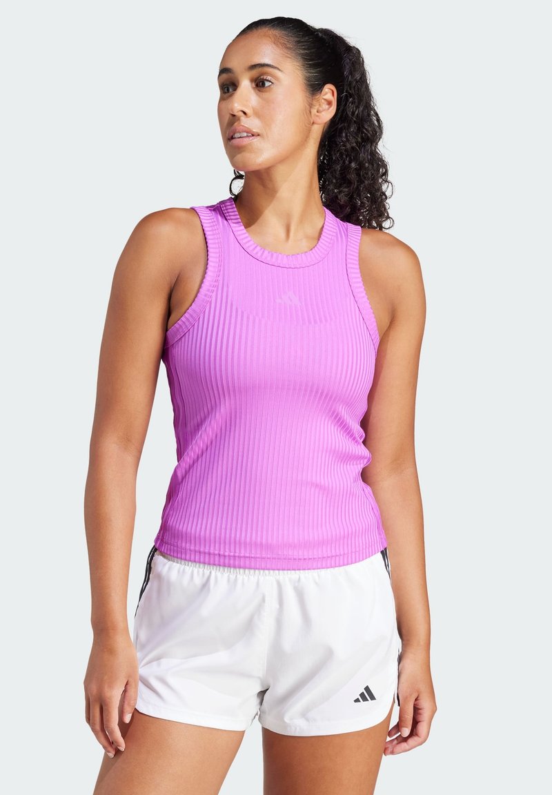 Roze geribde tanktop met een ronde halslijn en mouwloos ontwerp, gecombineerd met witte sportshorts voorzien van zwarte accenten en logo.