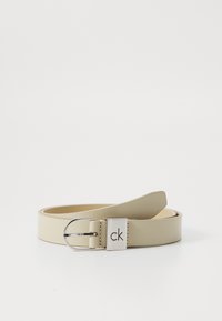Ceinture en cuir beige avec une boucle rectangulaire en argent portant les initiales "ck". Texture lisse avec un design simple.