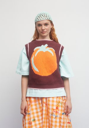 Strikket sweater i vinrød med et orange græskarprint. Lag-på-lag over en lys mintfarvet kortærmet top. Nederdel med orangeternet mønster og tekst.