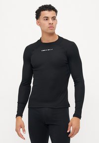Chemise de sport noire à manches longues en tissu extensible, avec un col rond, une coupe ajustée et un logo blanc sur la poitrine.