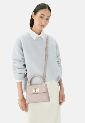 Maglione azzurro chiaro con colletto bianco, abbinato a una piccola borsa strutturata rosa pallido con hardware dorato e manico superiore.