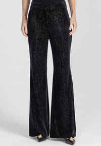 Czarne aksamitne dzwony z teksturowanym, błyszczącym wykończeniem. Posiadają wysoki stan i gładki pas, odpowiednie do noszenia na formalne lub codzienne okazje.