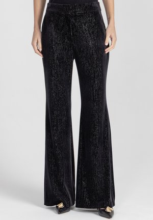 Czarne aksamitne dzwony z teksturowanym, błyszczącym wykończeniem. Posiadają wysoki stan i gładki pas, odpowiednie do noszenia na formalne lub codzienne okazje.