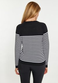 Gestreifter schwarz-weißer Pullover mit tailliertem Schnitt, rundem Halsausschnitt und gerippten Bündchen. Weicher Stoff mit kontrastierenden Streifen über den Rücken.