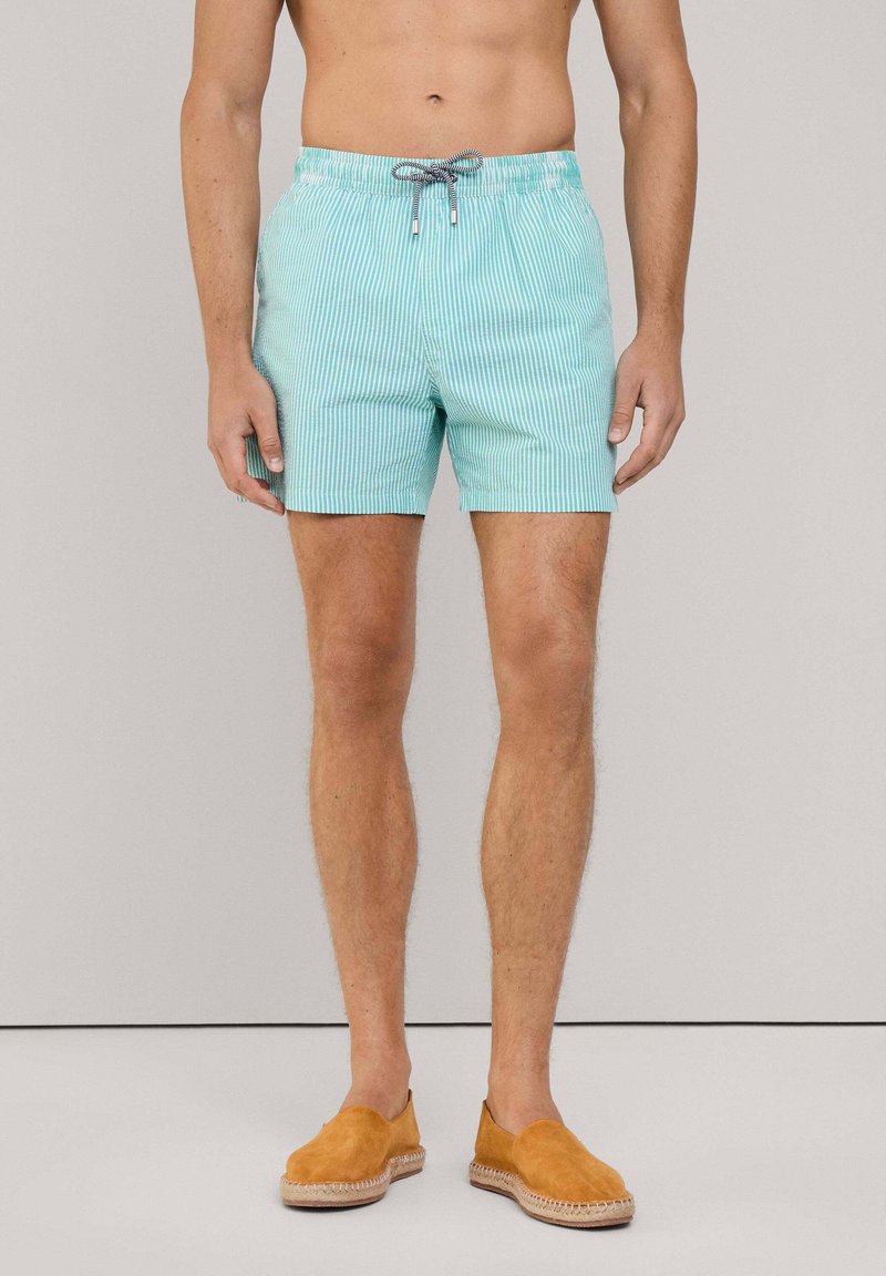 Costumi da bagno a righe turchesi con elastico in vita e cordoncino. I pantaloni hanno una trama leggera e liscia e una lunghezza fino a metà coscia.
