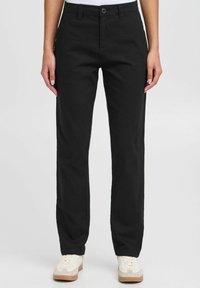 Pantaloni neri a gamba dritta realizzati in cotone con chiusura a bottone. Presentano tasche laterali e una superficie liscia, abbinati a sneakers leggere.