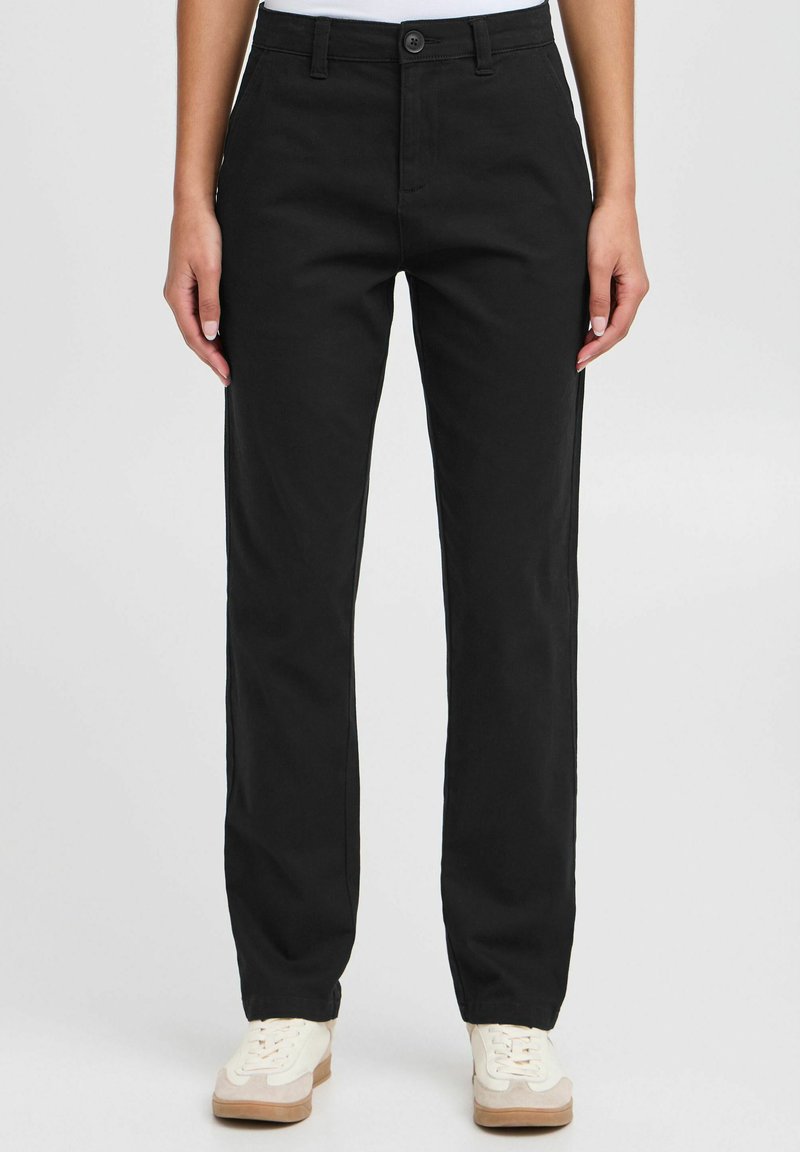 Pantaloni neri a gamba dritta realizzati in cotone con chiusura a bottone. Presentano tasche laterali e una superficie liscia, abbinati a sneakers leggere.