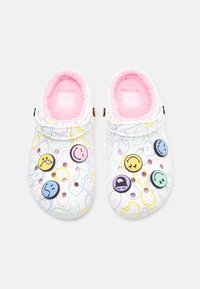 Hosszú szőrme bélésű klumpák fehér gumiból készült külsővel, színes mosolygós arc dekorációkkal és többszínű, hullámos mintákkal.