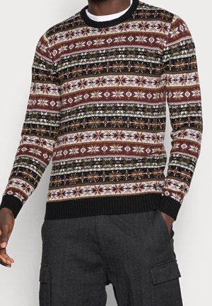 Homme portant un pull à motifs Fair Isle multicolores avec des poignets et un ourlet côtelés noirs, associé à un pantalon cargo gris foncé.