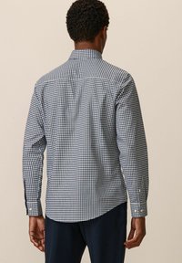 Chemise à manches longues avec un motif vichy bleu et blanc, poignets boutonnés et un col classique, fabriquée en coton léger.