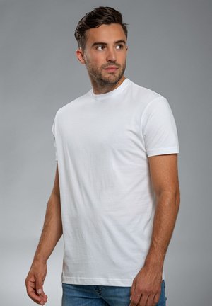 White short-sleeve t-shirt made of cotton; features a crew neckline and a smooth texture. Worn with blue jeans. Simple design.