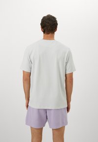 Lysegrå kortærmet t-shirt med tekstureret stof, synlige sømme og en afslappet pasform, sammen med lavendelshorts.