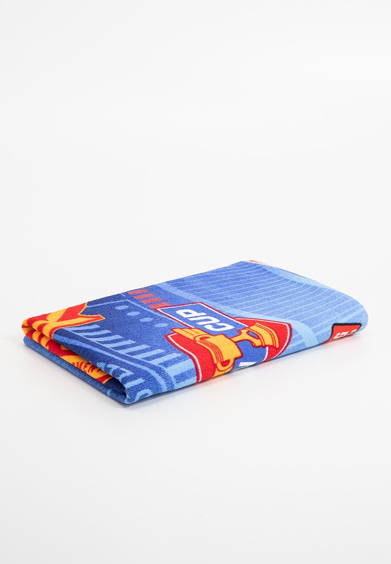 Toalla azul con un diseño gráfico en rojo y amarillo que incluye un logotipo. Textura suave con forma rectangular doblada.