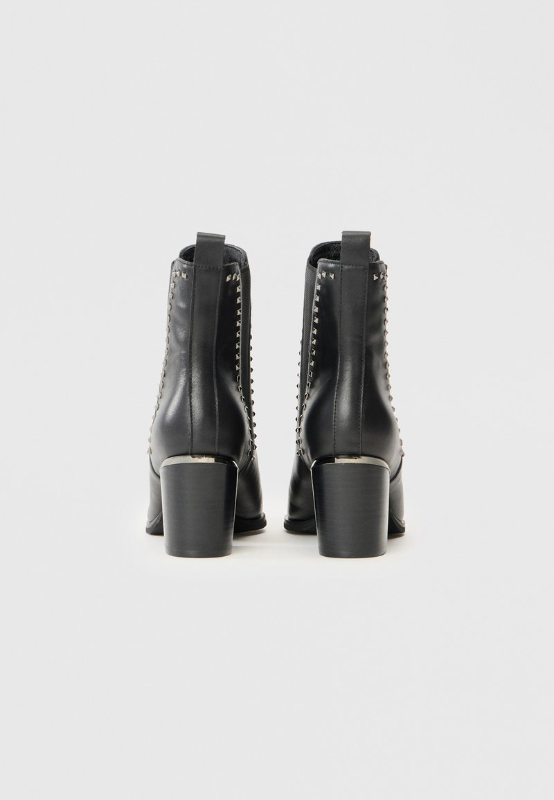 Schwarze Leder-Ankle-Boots mit glatter Textur und dekorativen Nieten entlang der Rückseite, ausgestattet mit einem stabilen Blockabsatz.