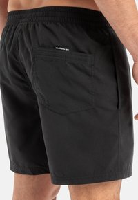 Bañador negro con cintura elástica, un bolsillo trasero y detalle del logo. Tela ligera, diseño informal y longitud por encima de la rodilla.