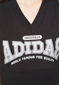 Fekete V nyakú pamut póló, középen feltűnő szürke felirattal: "ADIDAS" és "VILÁGSZINTŰ MINŐSÉGÉRT", a póló elején.