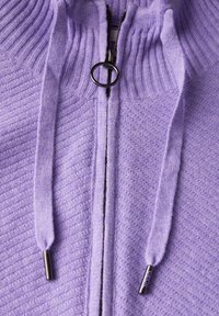 Haut de hoodie zippé lilas en tissu texturé. Caractéristiques : col montant avec bord côtelé, cordons de serrage et quincaillerie métallique.