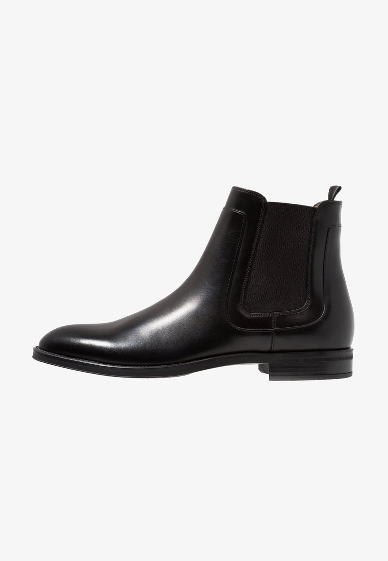 Botte Chelsea en cuir noir avec panneaux latéraux élastiques, bout arrondi et petit talon empilé. Surface lisse avec des détails de couture minimalistes.