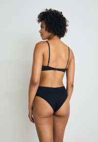 Zwart lingeriesetje bestaande uit een gladde bralette met verstelbare bandjes en een bijpassende hoogoplopende onderkant, gemaakt van zachte stof met minimale naden.