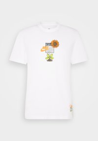Camiseta blanca de algodón con un gráfico de un girasol y una hoja, con un patrón cuadrado gris y el logo de Nike en naranja en el centro.