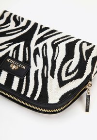 Pochette à motif zèbre avec un tissu texturé noir et blanc, des accents en cuir noir et une fermeture éclair dorée avec une étiquette de logo.