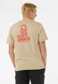 Camiseta de algodón beige con un gran gráfico rojo y estampado de "Search" en la parte posterior, de mangas cortas y ajuste clásico.