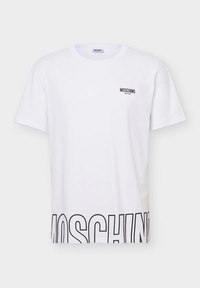 Άσπρο κοντομάνικο t-shirt Moschino Active με μικρό λογότυπο στο στήθος και μεγάλο μαύρο περίγραμμα κειμένου που φαίνεται μερικώς κατά μήκος του κάτω τελειώματος.
