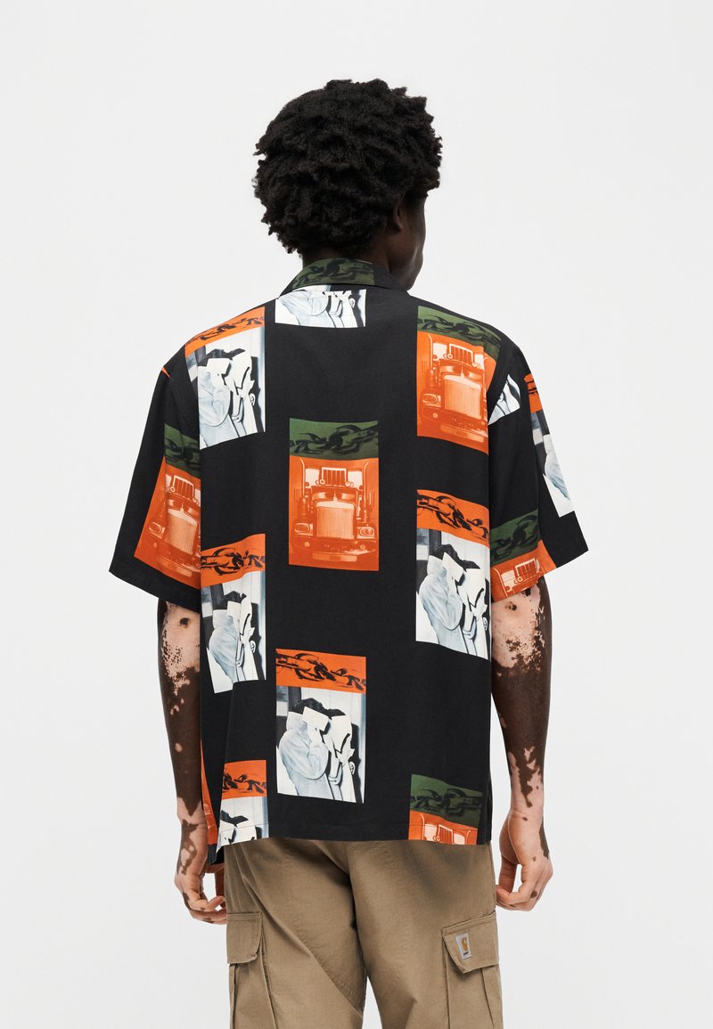 Camicia a maniche corte in tessuto nero con motivo a rettangoli colorati con stampe grafiche in arancione, verde e bianco. Vestibilità comoda.