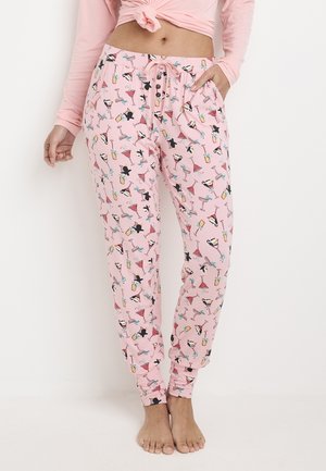 Pink pajama pants made of soft fabric, featuring a repeated pattern of cocktails, hats, and cats. Designed with an elastic waistband and pockets.