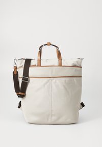 Sac fourre-tout beige clair avec des accents en cuir marron, anses supérieures et une bandoulière réglable marron foncé. Fermeture éclair avec poche avant.