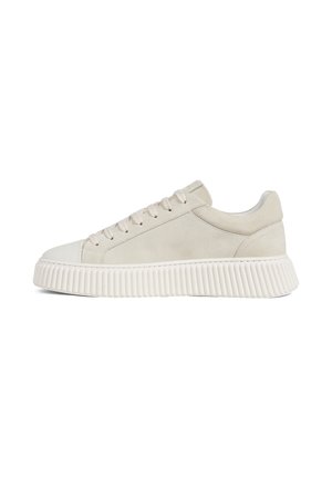 Low-top beige suede sneaker with lace-up front and thick ridged white rubber sole, side view on white background.