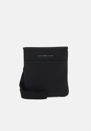 Czarna skórzana torba na ramię Tommy Hilfiger z przednią kieszenią i regulowanym paskiem na ramię na jednolitym tle.