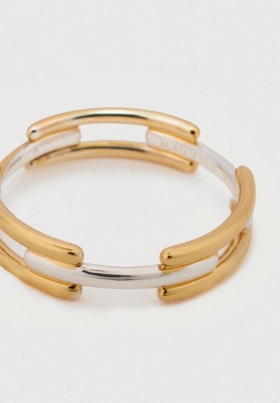 Zlato in srebro prepletena zapestnica z gladko teksturo, zaobljenimi robovi in sodobnim geometrijskim oblikovanjem.