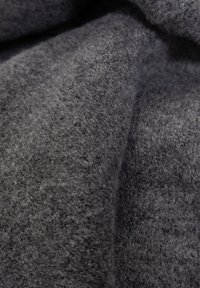 Tela de lana gris con una superficie suave y texturizada. Presenta un tejido denso y variaciones sutiles en el color, lo que proporciona una apariencia acogedora.