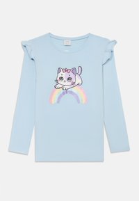 Hellblaue Langarmbluse mit einem verspielten Katzenmotiv über einem Regenbogen. Rüschenakzente an den Schultern sorgen für Textur. Aus weichem Baumwollmaterial.