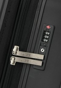 Cremallera de maleta negra con dos tiradores plateados de la marca Gabol y un candado de combinación de tres dígitos aprobado por la TSA configurado en 000.
