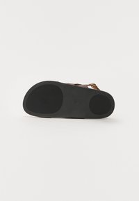 Sandalias marrones con una suela exterior de goma negra texturizada, que cuentan con una correa ajustable y un diseño minimalista. Aptas para uso casual.